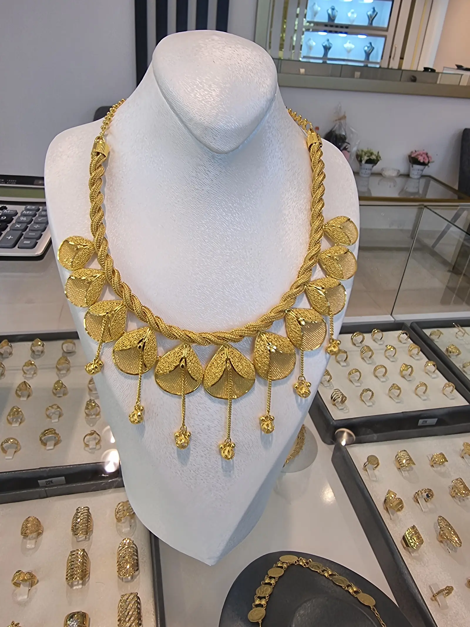 Handgearbeitetes Collier aus Gold mit Münzdekor auf einer Schmuckbüste